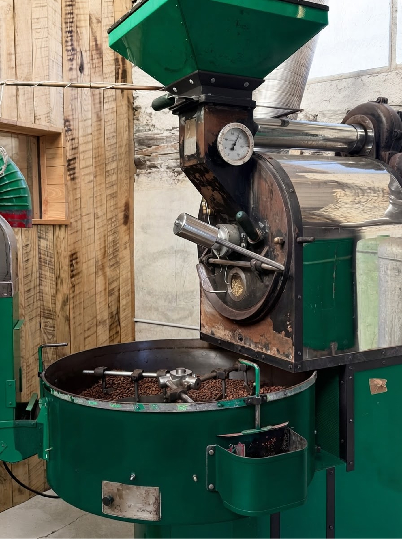 La torréfacteuse verte de l'atelier, remplie de grains de café