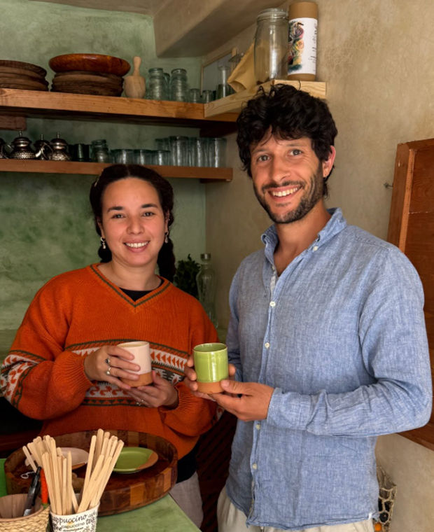 Un homme et une femme souriants, une tasse à la main, dans une cuisine en bois